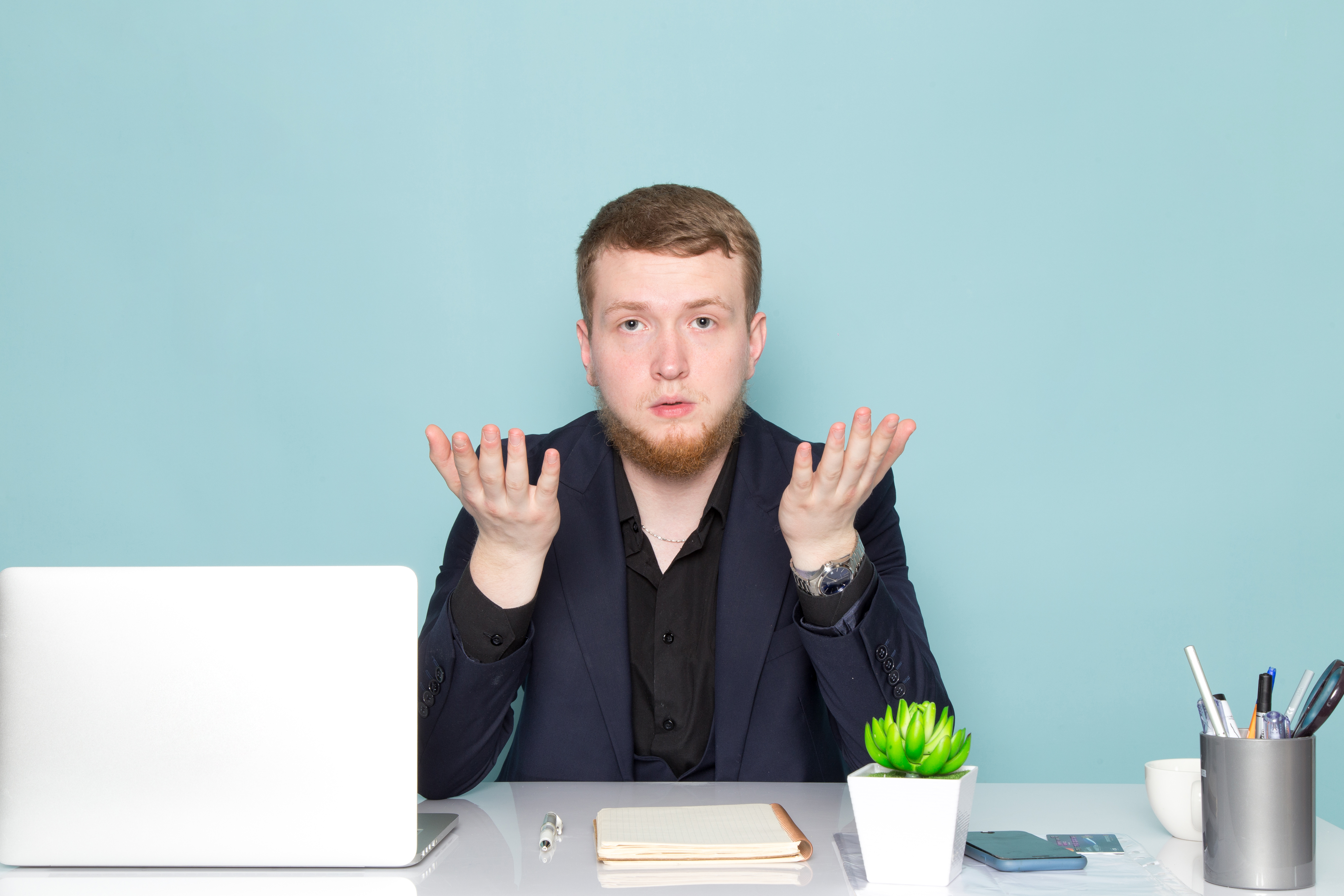 front-view-young-attractive-male-with-beard-black-dark-classic-modern-suit-emotions-with-raised-hands-blue-space.jpg