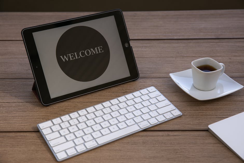 Bureau élégant avec une tablette affichant 'BIENVENUE', accompagnée d'un clavier et d'une tasse de café sur une table en bois.